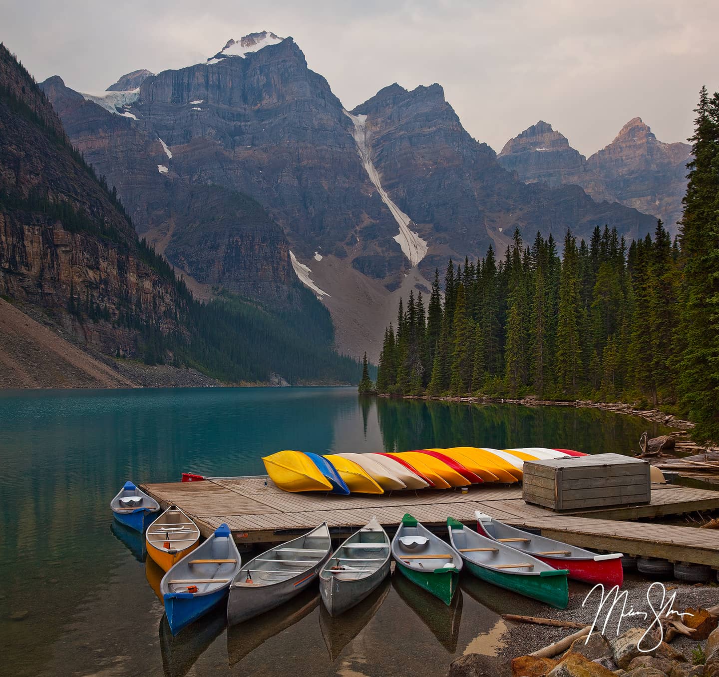Colorful canoes at dock on Moraine Lake with mountains in 