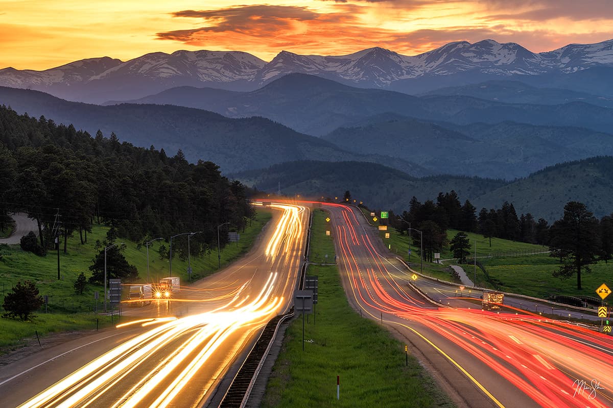 Vehicles driving to and from the mountains along I-70 near Denver in the foothills of the Colorado Rockies at sunset