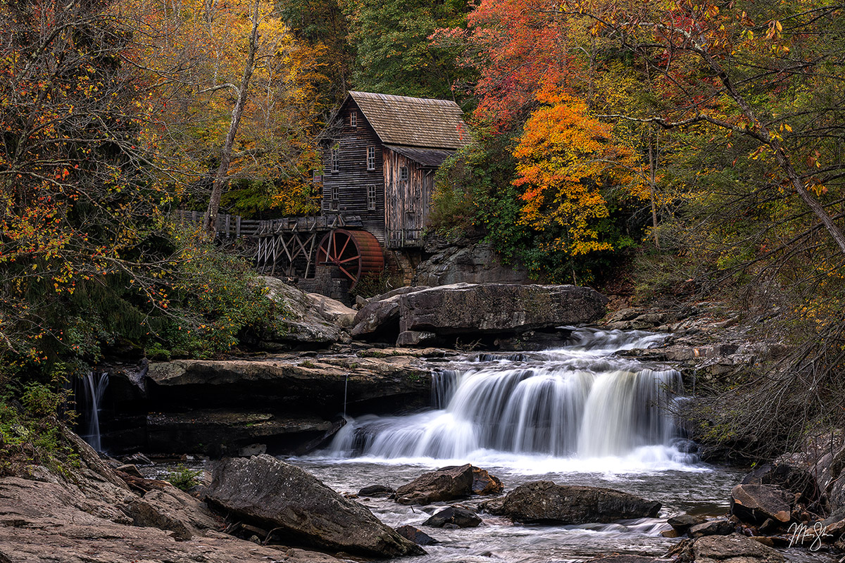 Historic Glade Creek Grist Mill surrounded by autumn foliage and flowing mountain waters in Babcock State Park West Virginia